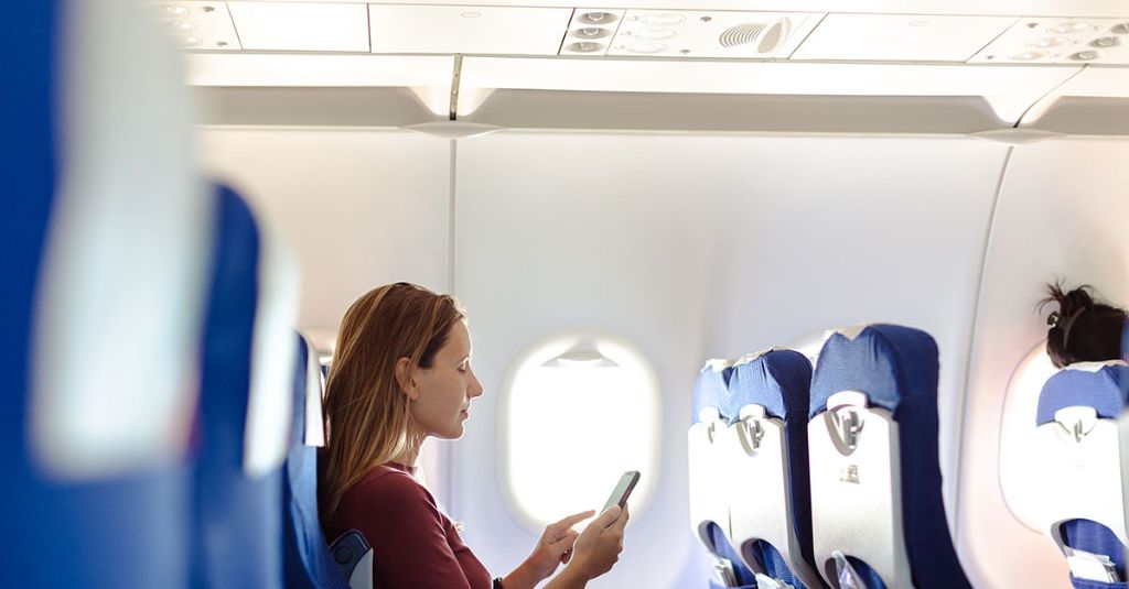 woman using her smarthone in an airplane cabin