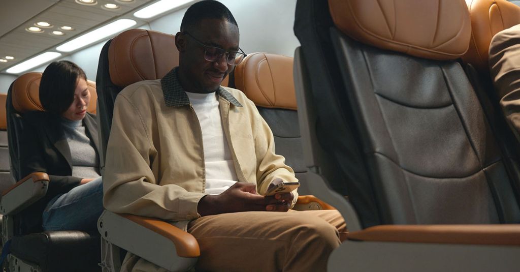 Man sitting on a train looking at his phone.